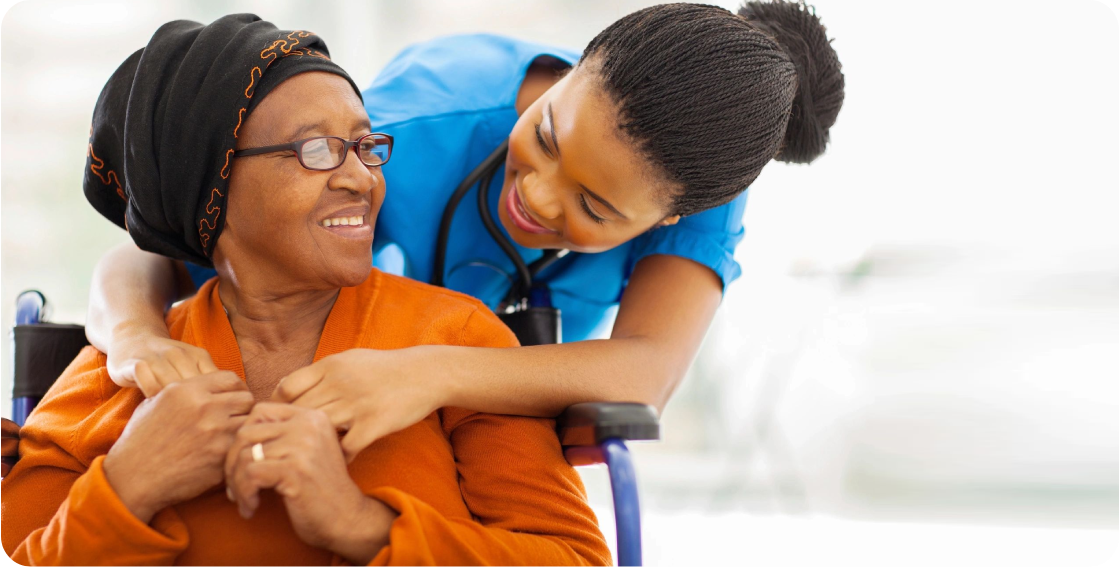 A nurse is hugging an elderly woman in a wheelchair.