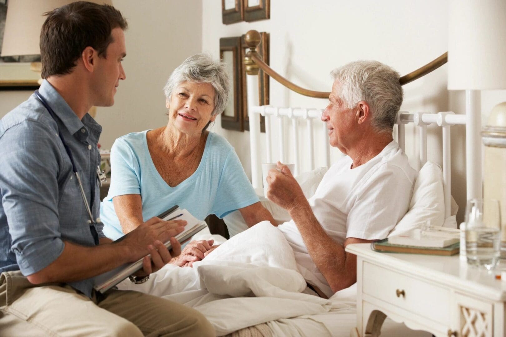 A man and two women sitting on top of a bed.